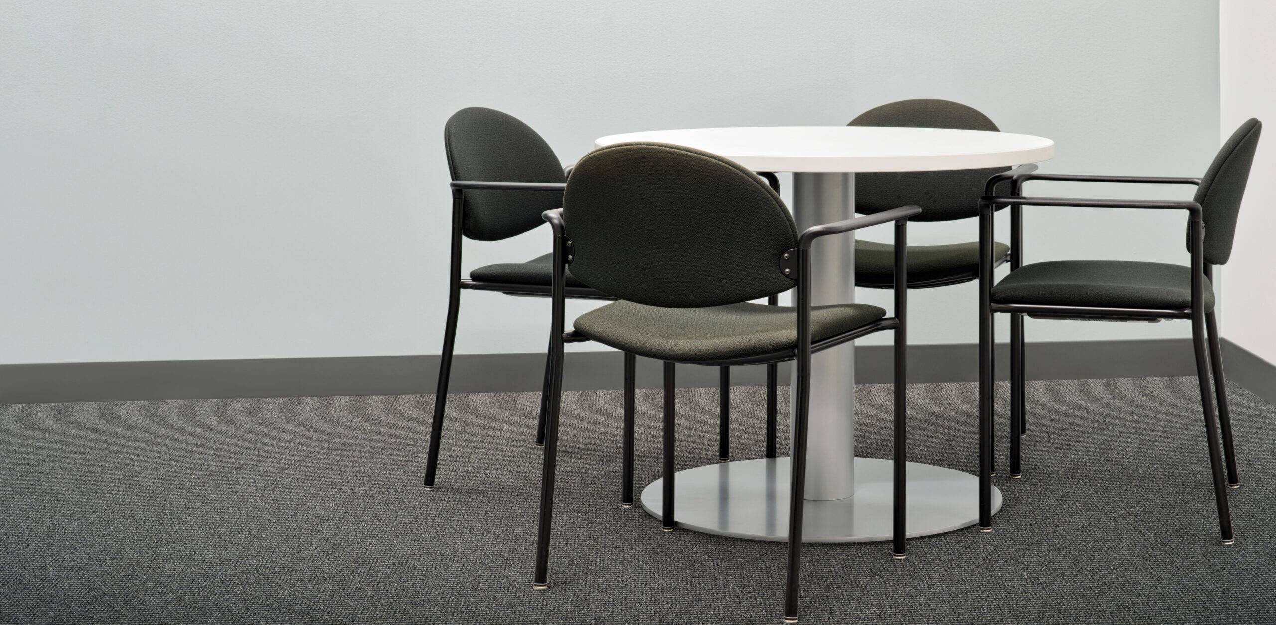 Round table four black chairs furniture in office setting gray c